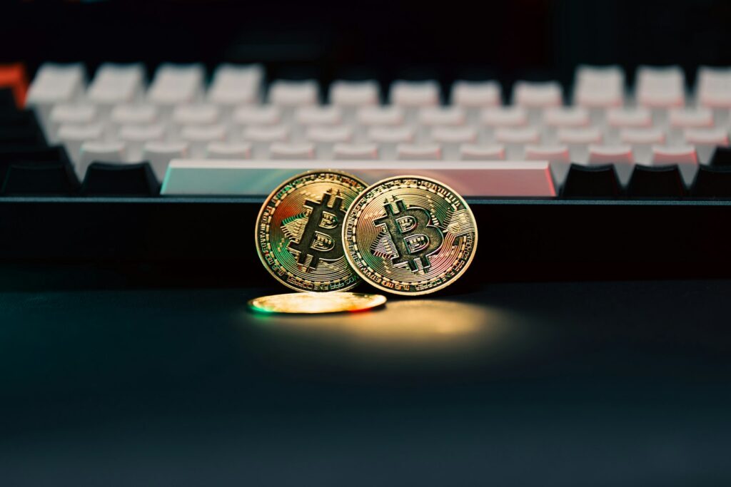 Two Bitcoin tokens sitting next to a computer keyboard