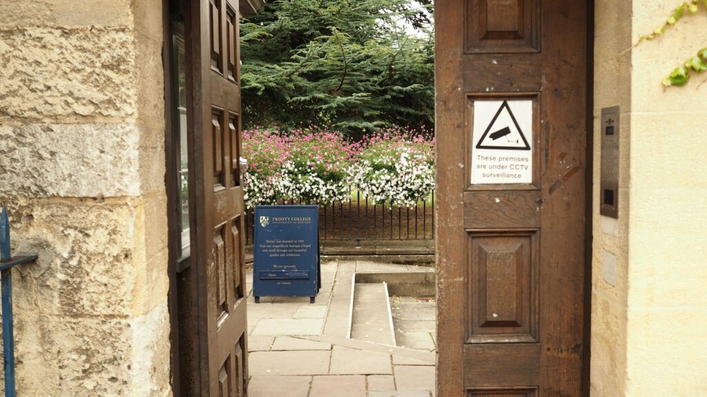 Open wooden gate with a CCTV warning sign, the kind of entrance needing access checks