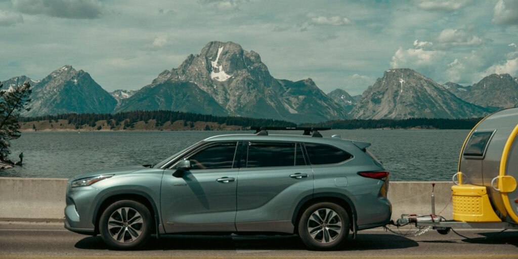 SUV towing a trailer with mountains and a lake in the background